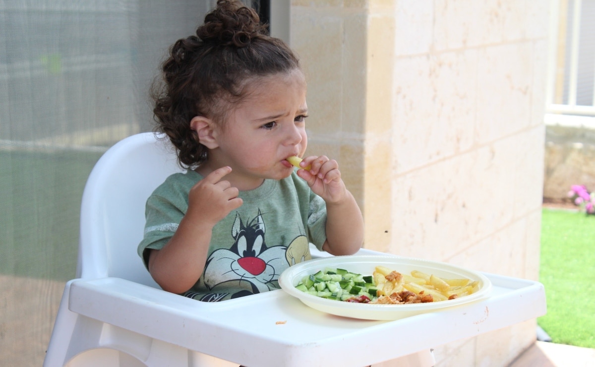 niña comiendo verduras con la mano en su sillita