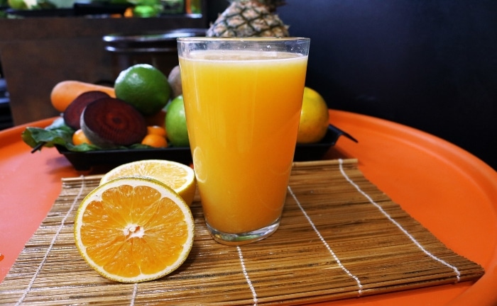 zumo de naranja exprimido en un vaso encima de un mantel