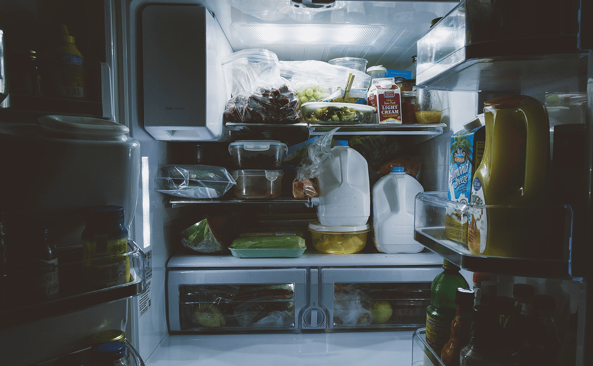 Un frigorífico muy lleno de comida con la puerta abierta.