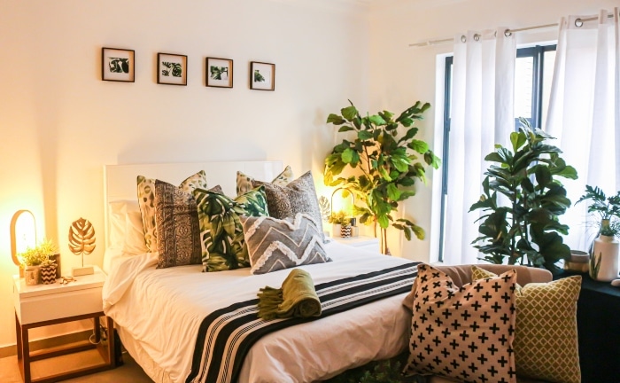 habitación un poco recargada, con plantas, cojines y aire tropical
