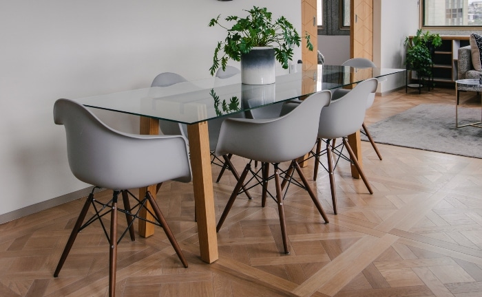 mesa de cristal estilo escandinavo con 4 sillas en gris y macetero