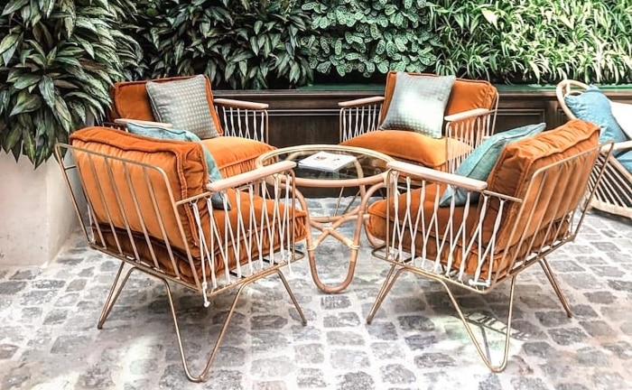 sillas y mesa de terraza en tonos validos y fondo con plantas