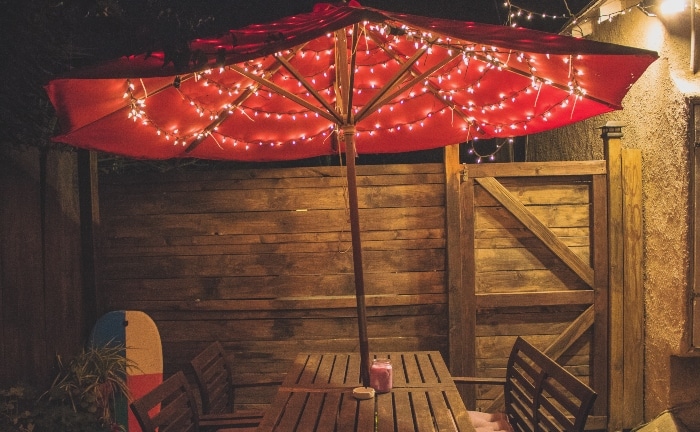 led y sombrilla roja en un porche con silla y mesas de madera