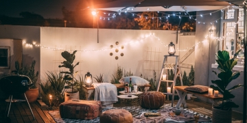 terraza de verano con luces, plantas, comida y bebida en el suelo sobre alfombra blanca y negra