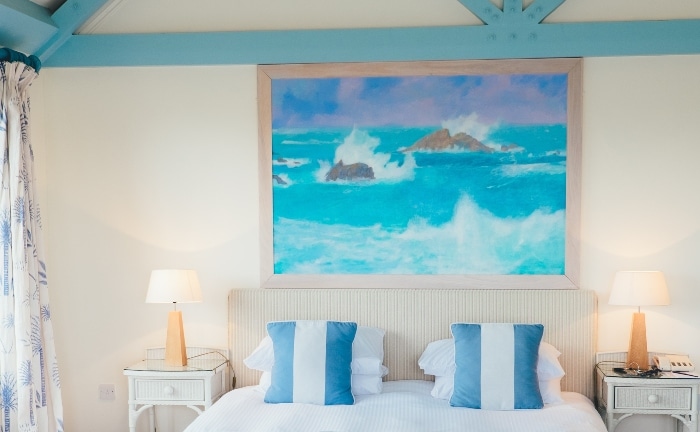 dormitorio en azules, con cuadro sobre la cama y cojines de rayas