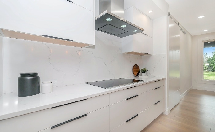vista de una cocina blanca sin apenas objetos en la encimera, suelo de madera y mucha luminosidad