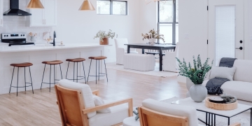 cocina blanca con tabuetes de madera abierta a salón son decoración en blanco y madera con plantas