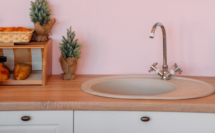 detalle de grifo de cocina con pared en rosa palo y muebles blancos