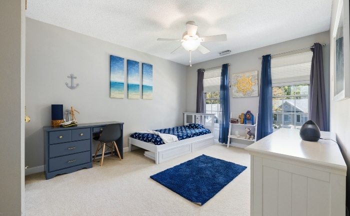 dormitorio en tonos blancos y azules, con gran ventanal , alfombra, escritorio y cama individual