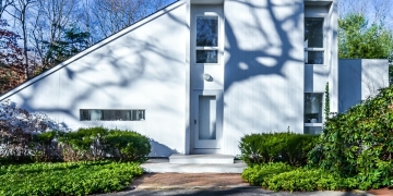 Fachada de una típica casa americana moderna, en blanco, con grandes ventanas y pequeño jardín cuidado