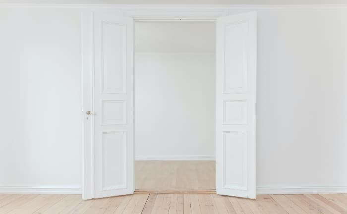 puerta lacada en blanco abatible doble, con paredes blancas y suelo de madera claro