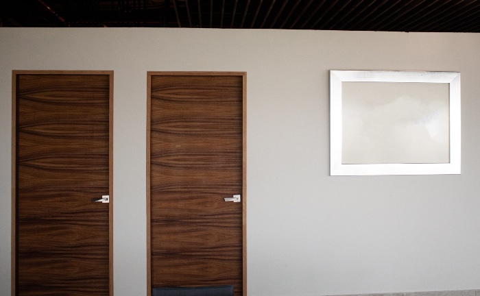 dos puertas de madera en pared beige con ventana metalizada